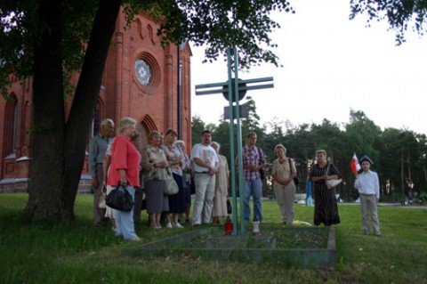 Przy Czerwonym Kościele, obok pomnika-krzyża „Straż Mogił Polskich”, ustanowionego niedaleko świątyni. Krzyż wzniesiono na cześć żołnierzy Armii Krajowej oraz jako pomnik dla cywilnej ludności miasteczka, wymordowanej w latach 1939-1945